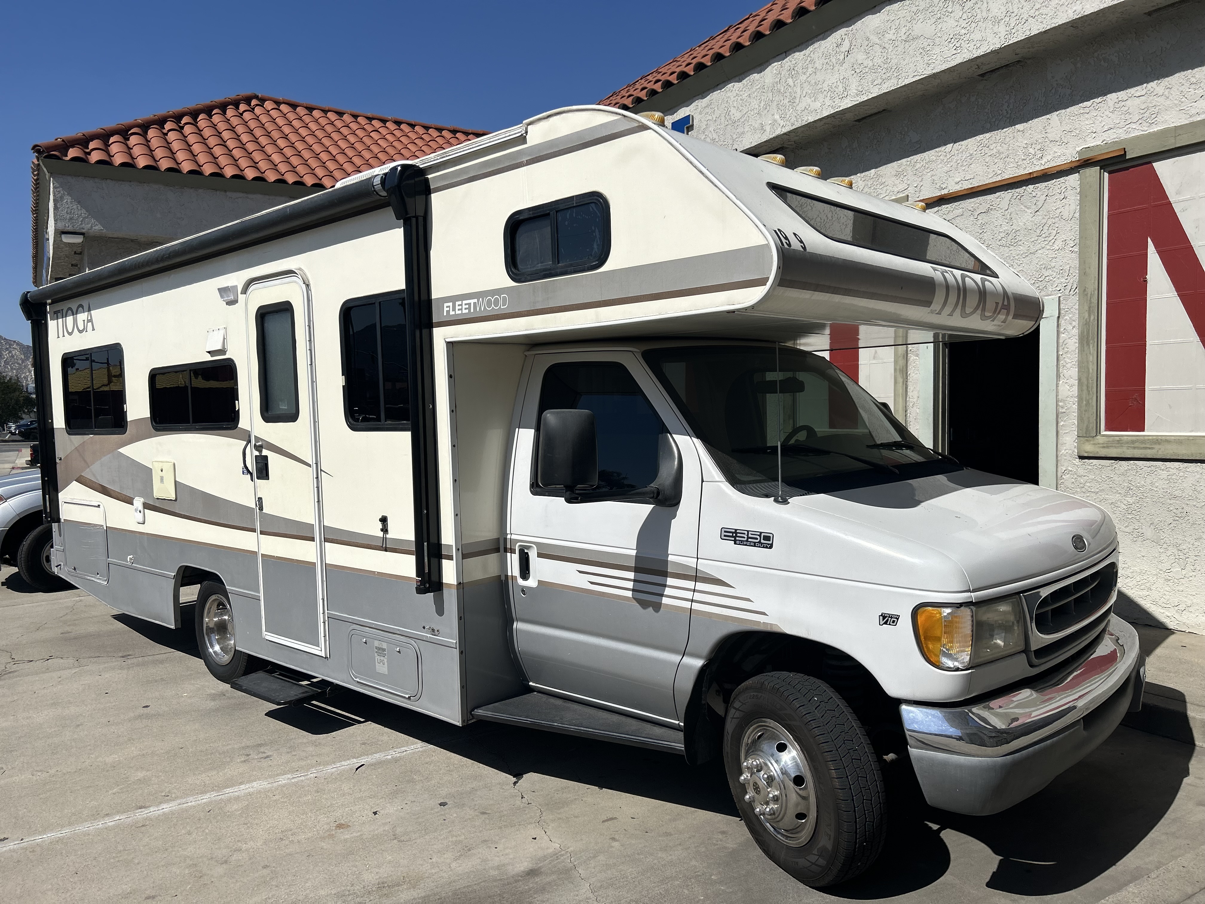 An RV with tinted windows parked at the shop