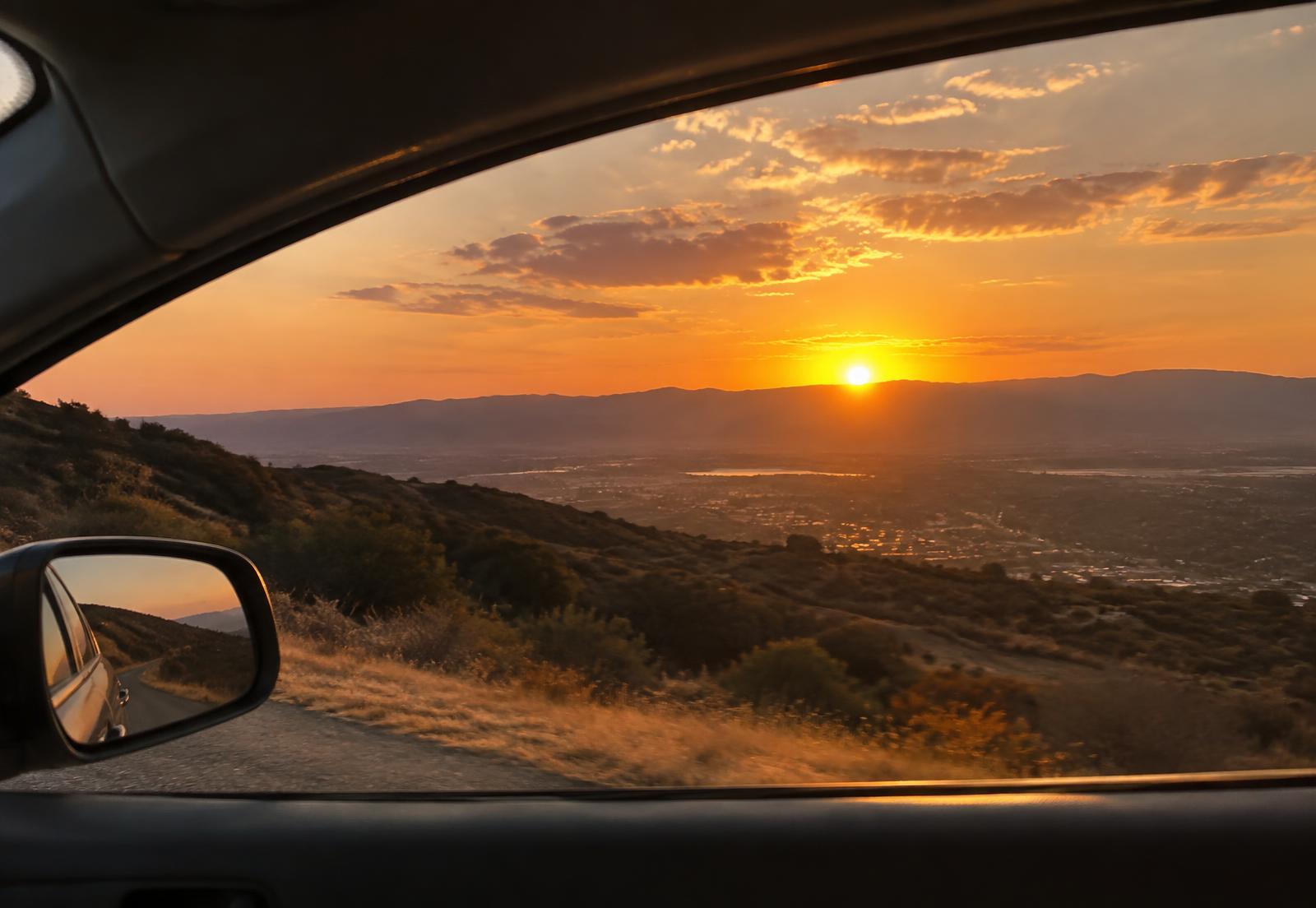 Sunset over the hills seen through a car window